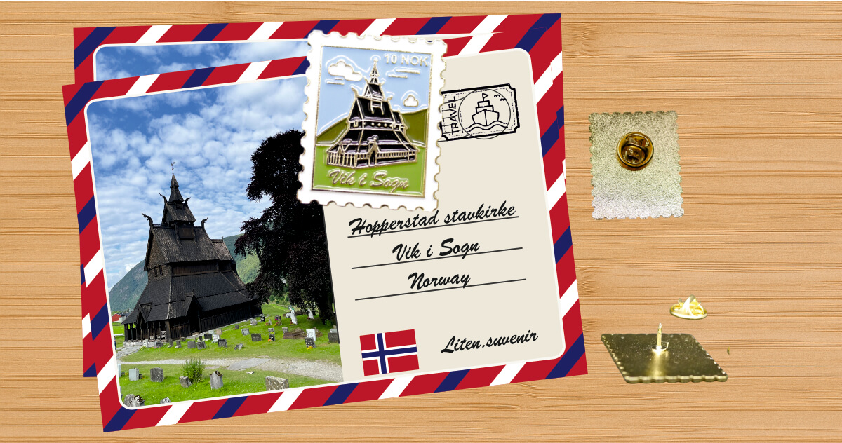 Emaliowany pin w kształcie znaczka pocztowego oraz pocztówka z Vik i Sogn w Norwegii na drewnianym tle.